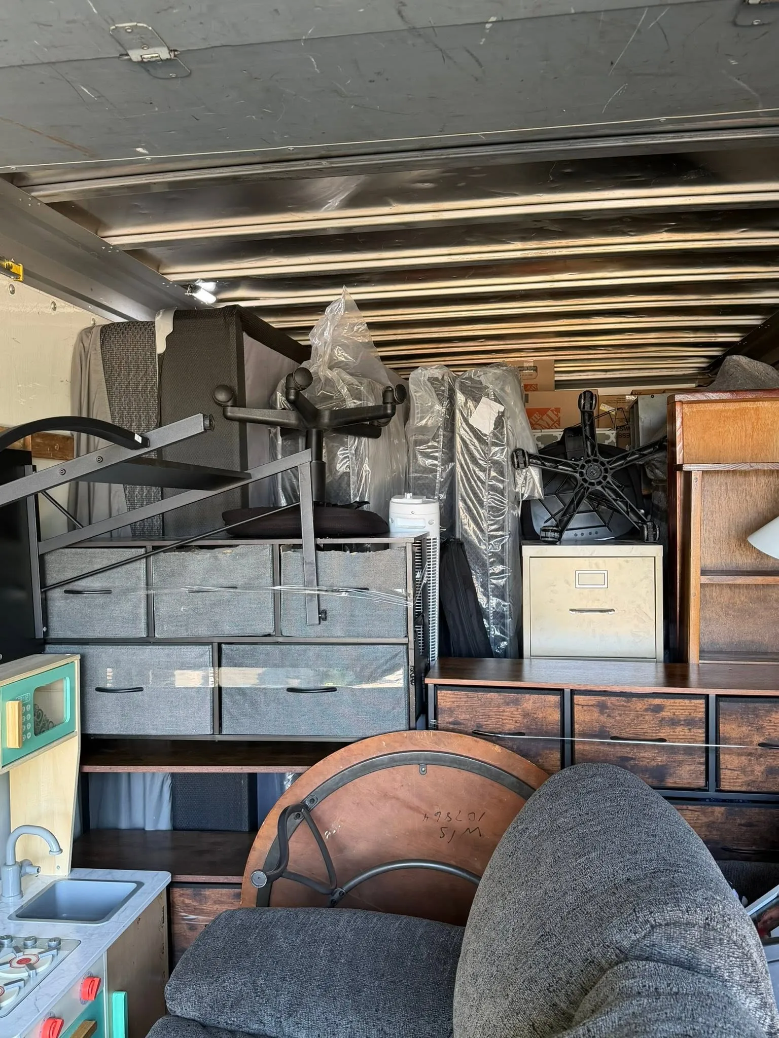 The box truck packed with a gray sectional, shelving, a dresser and boxes