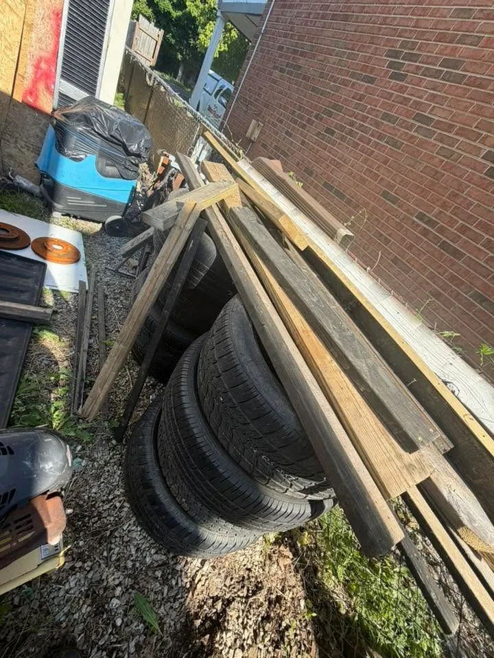 Old tires and scrap lumber leaned against a brick wall beside the junk pile