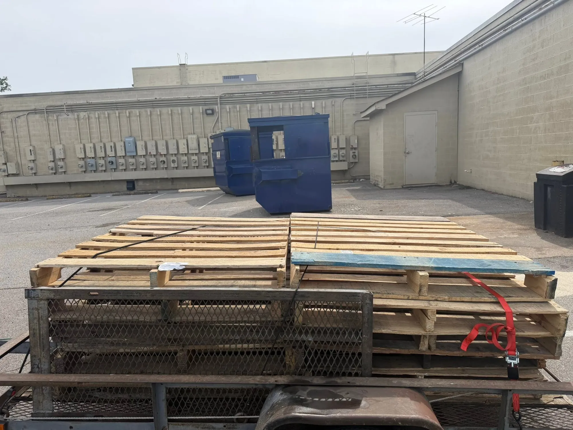 Wooden pallets stacked on a flatbed trailer behind a commercial building