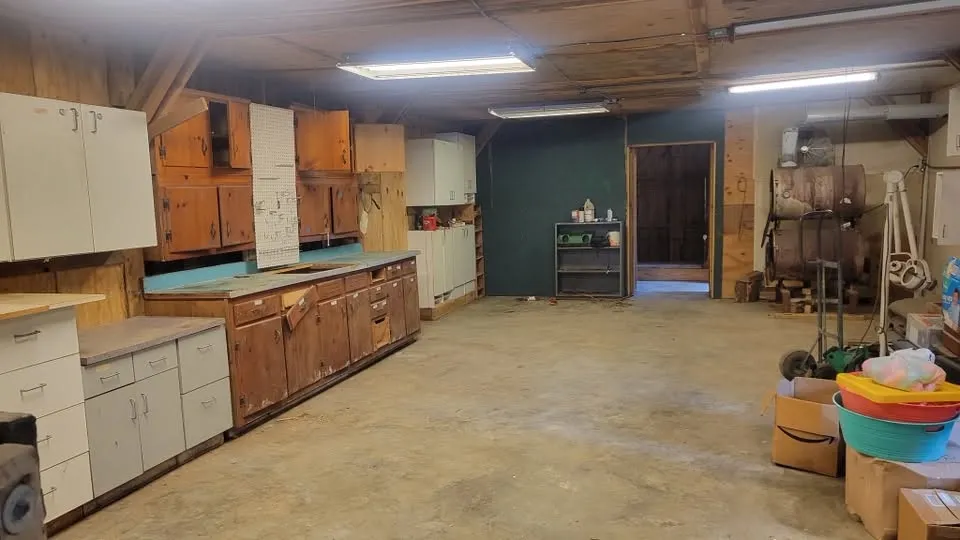 The same workshop emptied, the concrete floor bare and the cabinets clear